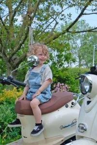 kindje lacht op retro scooter